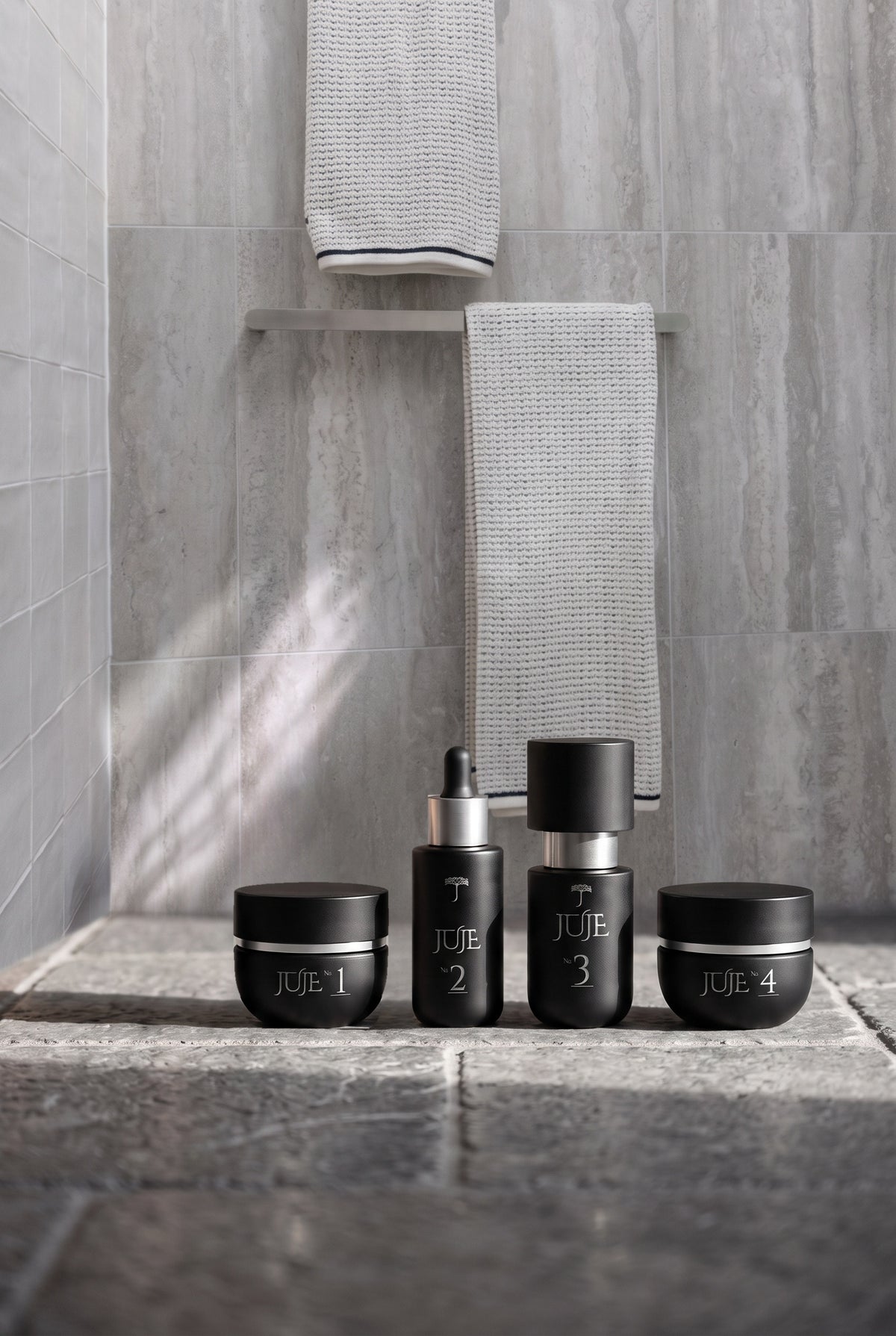 The four Juje formulas, No. 1 to No. 4, lined up on a stone ledge in a softly lit shower